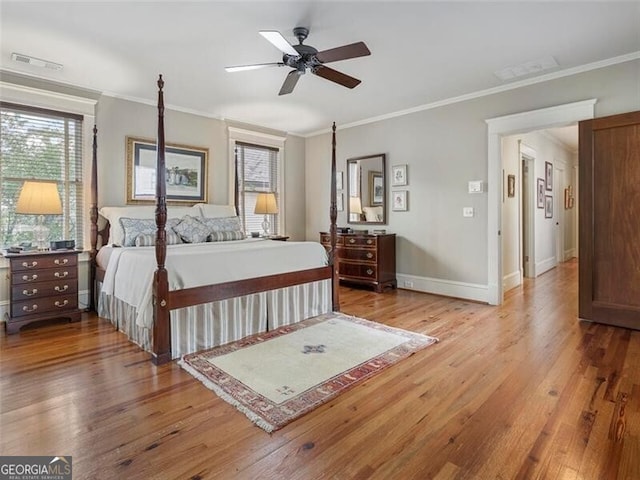 bedroom with ornamental molding, wood finished floors, visible vents, and baseboards