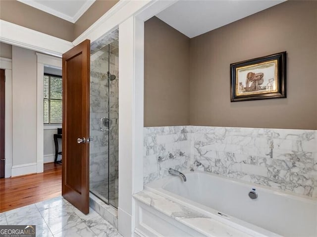 bathroom featuring a stall shower, marble finish floor, baseboards, and a bath