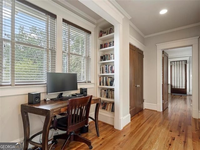 office area featuring ornamental molding, light wood-type flooring, baseboards, and built in shelves