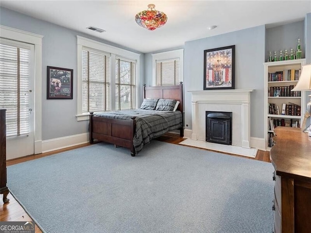 bedroom with wood finished floors, visible vents, baseboards, and multiple windows