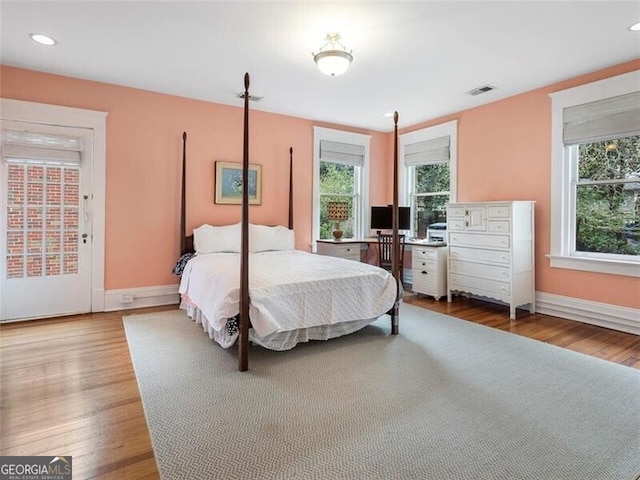 bedroom with wood finished floors, visible vents, baseboards, and multiple windows