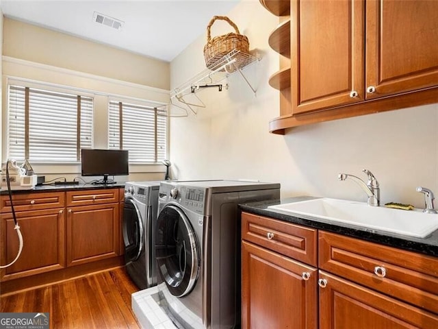 clothes washing area featuring a sink, visible vents, cabinet space, dark wood-style floors, and washer and clothes dryer