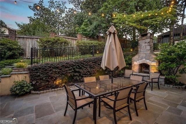 view of patio / terrace featuring a fenced backyard, an outdoor stone fireplace, and outdoor dining space