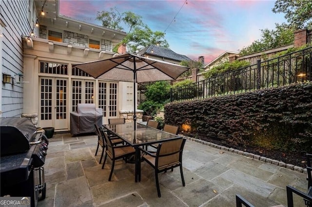 view of patio / terrace featuring french doors, outdoor dining space, fence, and a grill