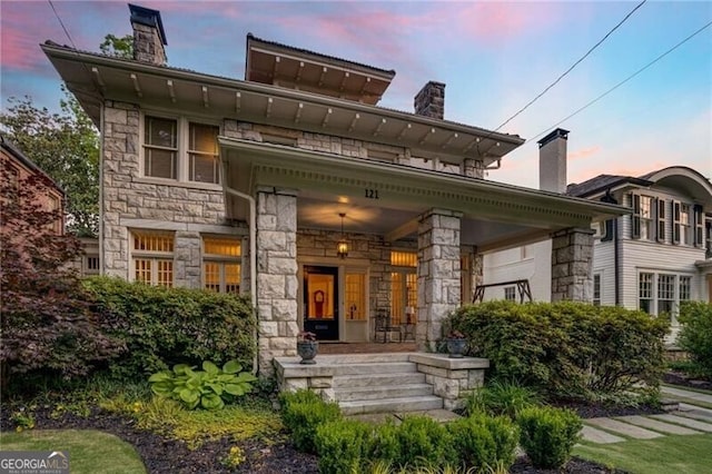 rear view of property with covered porch and a chimney