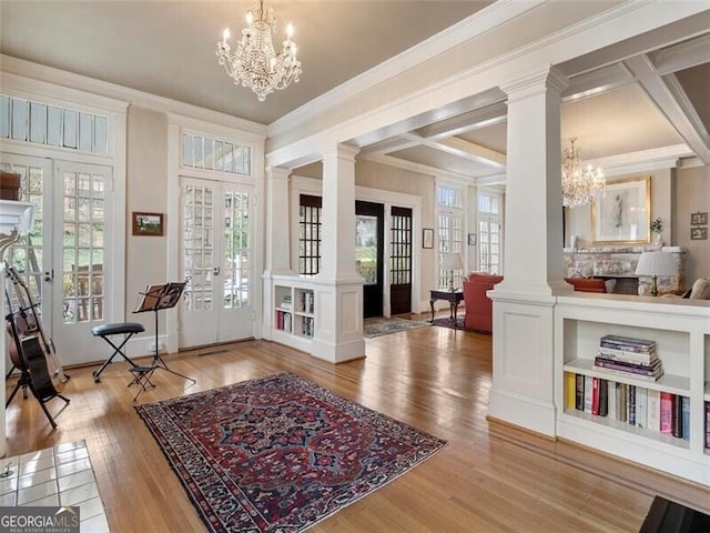 entrance foyer with ornate columns, plenty of natural light, a notable chandelier, and french doors