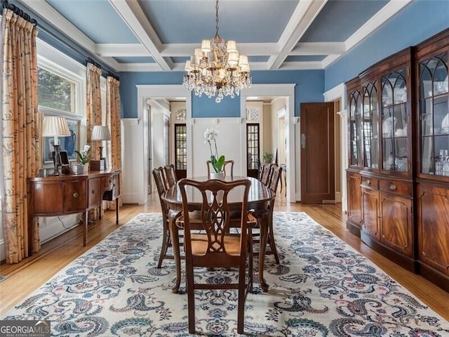 dining space featuring a chandelier, coffered ceiling, and light wood-style flooring