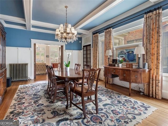 dining area with coffered ceiling, radiator heating unit, wood finished floors, beamed ceiling, and a chandelier