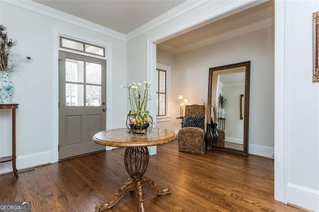 foyer with ornamental molding, wood finished floors, visible vents, and baseboards