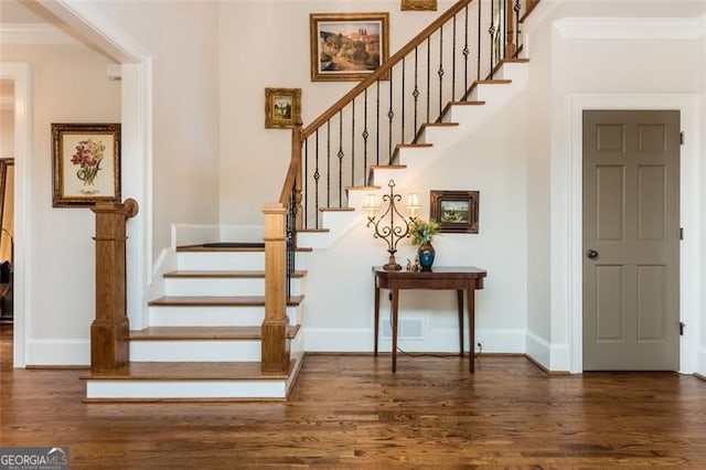 stairs featuring crown molding and wood finished floors