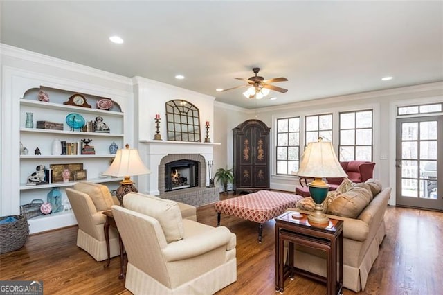 living room with crown molding, wood finished floors, a ceiling fan, and a wealth of natural light
