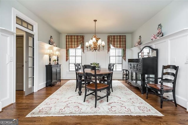 dining space featuring dark wood-type flooring and an inviting chandelier