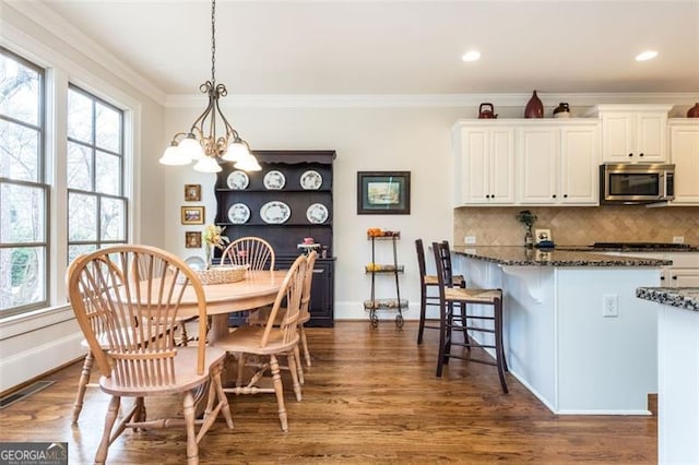 dining area featuring a healthy amount of sunlight, visible vents, dark wood finished floors, and crown molding