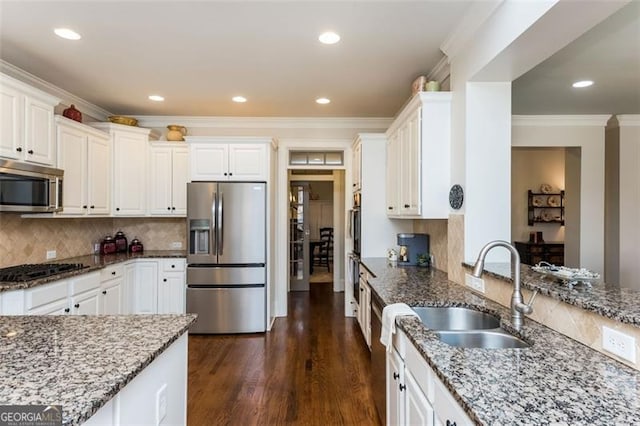 kitchen with crown molding, stone counters, a sink, and stainless steel appliances