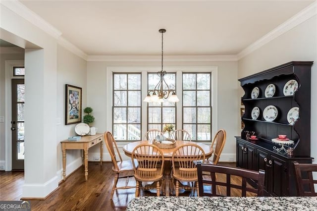 dining area featuring baseboards, dark wood-type flooring, crown molding, and a chandelier