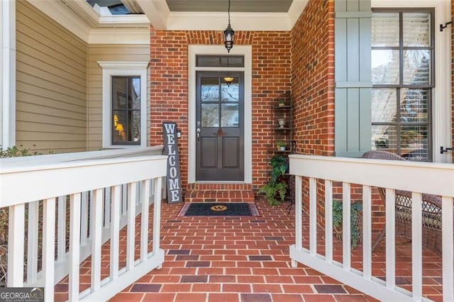 view of exterior entry featuring brick siding and a porch