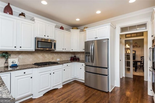 kitchen featuring decorative backsplash, dark stone counters, dark wood-type flooring, stainless steel appliances, and white cabinetry