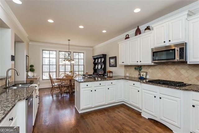 kitchen featuring appliances with stainless steel finishes, white cabinets, a sink, and a peninsula