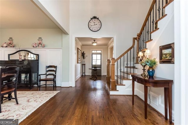 foyer entrance featuring stairs, baseboards, crown molding, and wood finished floors