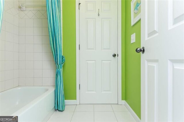 bathroom featuring tile patterned floors, shower / bath combo with shower curtain, and baseboards
