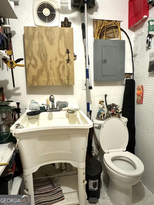 bathroom with electric panel, a textured wall, visible vents, and toilet