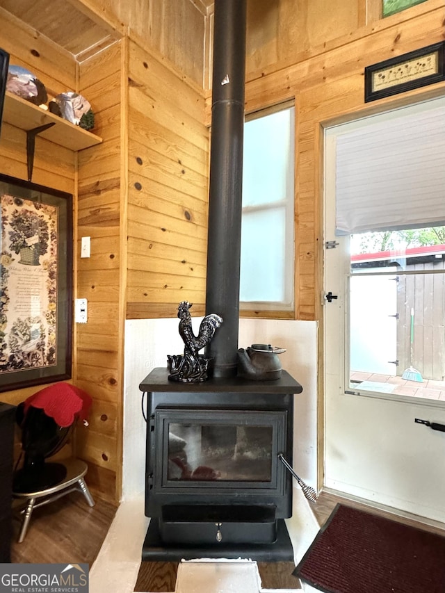 details with a wood stove, wooden walls, and wood finished floors