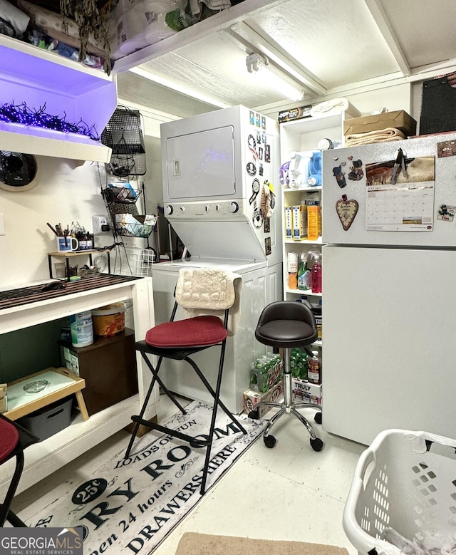 kitchen with concrete flooring, freestanding refrigerator, and stacked washer and clothes dryer