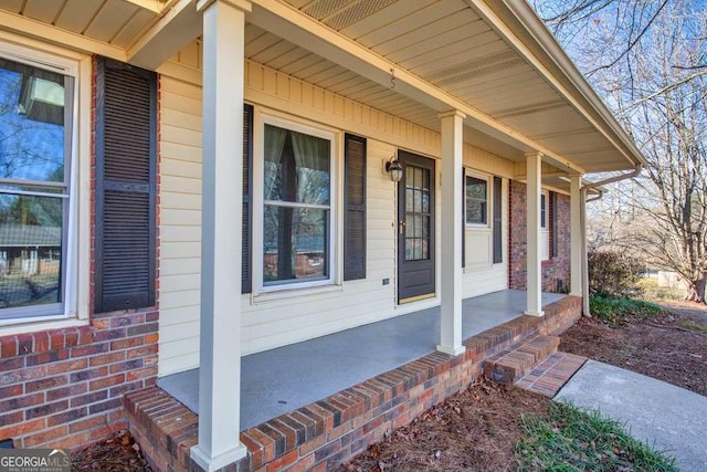 doorway to property with a porch and brick siding