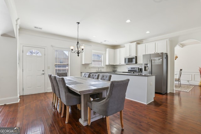 dining area with visible vents, arched walkways, dark wood finished floors, a notable chandelier, and recessed lighting