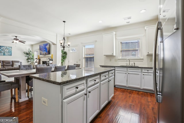 kitchen featuring visible vents, arched walkways, open floor plan, a center island, and freestanding refrigerator