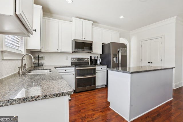 kitchen featuring white cabinetry, stainless steel appliances, a sink, and a center island