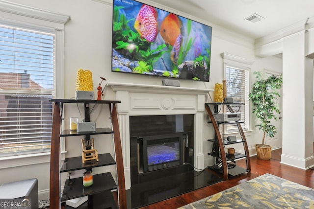 living area featuring baseboards, visible vents, dark wood-style flooring, and a glass covered fireplace