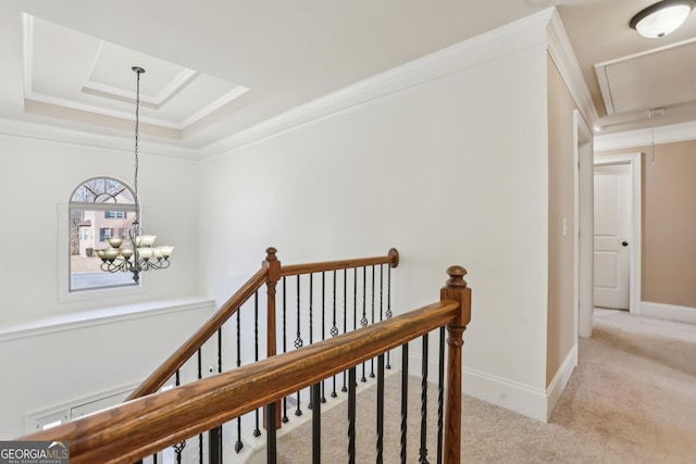 hall featuring a tray ceiling, light colored carpet, attic access, ornamental molding, and an upstairs landing