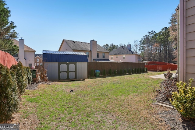 view of yard with a fenced backyard, a residential view, an outbuilding, a storage unit, and a patio area