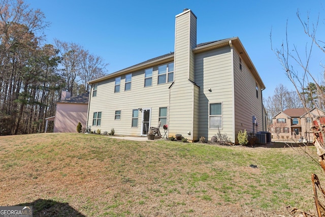 back of property with a chimney, cooling unit, and a lawn