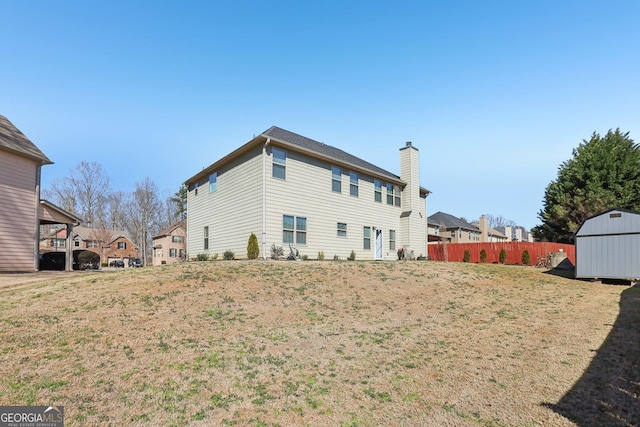 back of house featuring a lawn, fence, a shed, a residential view, and an outdoor structure