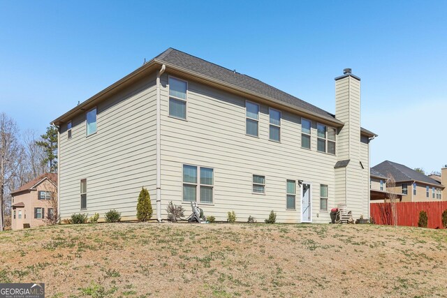 back of property featuring a chimney and fence