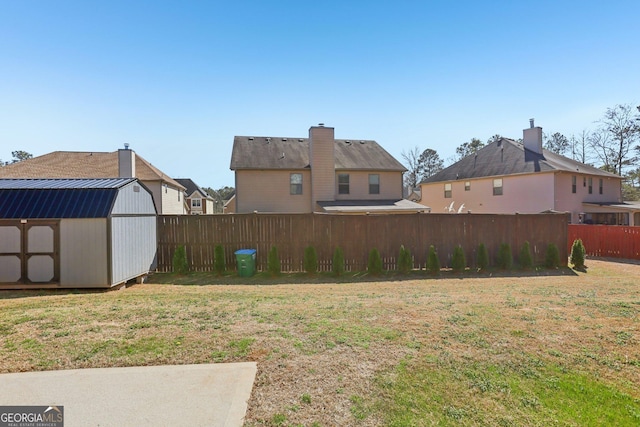 view of yard with fence, a storage unit, and an outbuilding