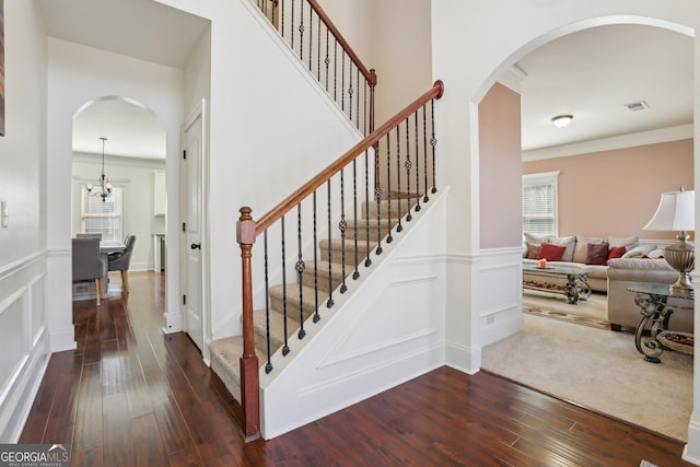 staircase featuring hardwood / wood-style flooring, visible vents, a decorative wall, and a chandelier