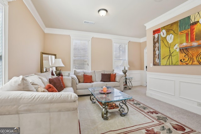 carpeted living room with a wainscoted wall, a decorative wall, visible vents, and crown molding