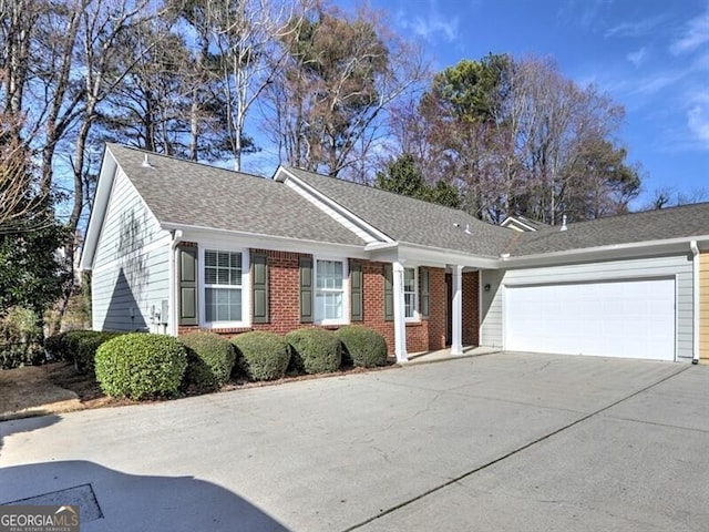 ranch-style home featuring a garage, concrete driveway, brick siding, and roof with shingles