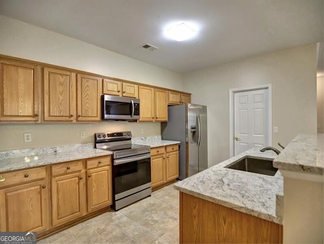 kitchen featuring a sink, visible vents, stainless steel appliances, and light stone counters