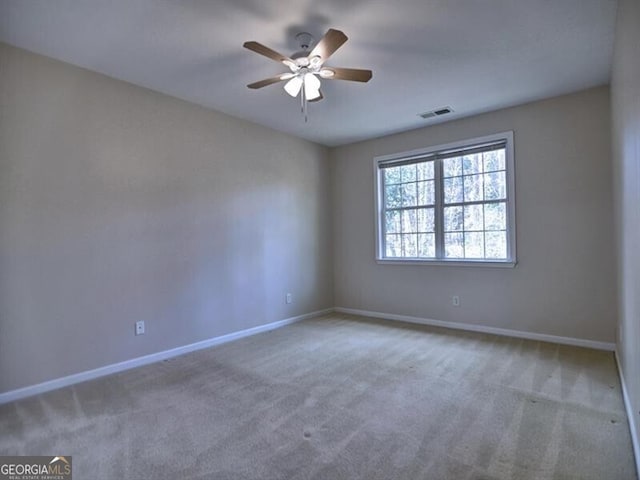 carpeted empty room with visible vents, baseboards, and a ceiling fan