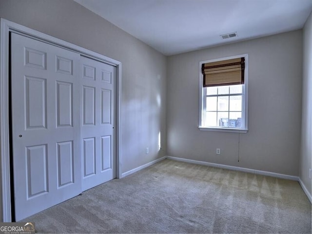 unfurnished bedroom featuring a closet, carpet, visible vents, and baseboards