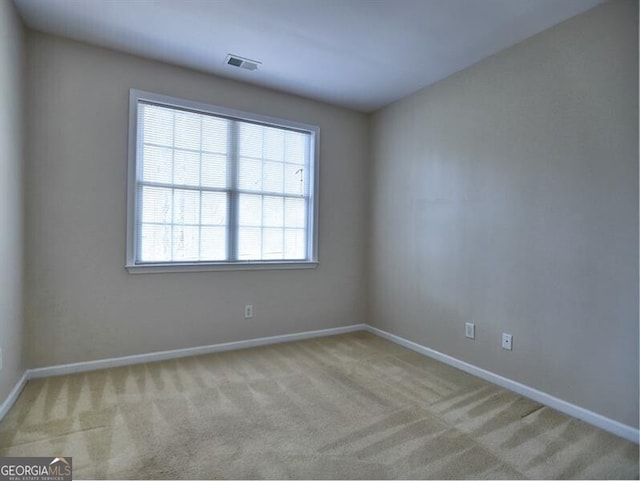 empty room featuring visible vents, baseboards, and light colored carpet