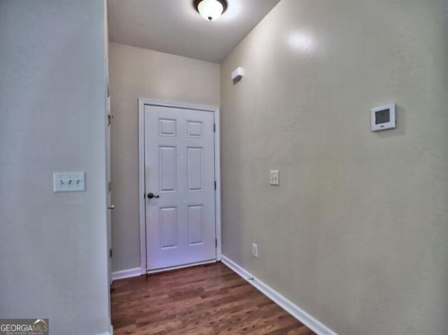 foyer with dark wood-type flooring and baseboards