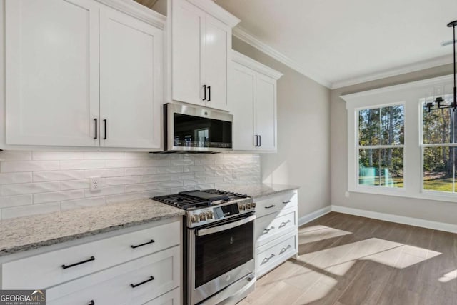 kitchen featuring stainless steel appliances, white cabinetry, ornamental molding, decorative backsplash, and pendant lighting