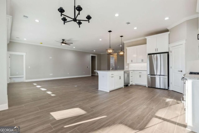 kitchen featuring light wood-style flooring, open floor plan, stainless steel appliances, white cabinetry, and pendant lighting