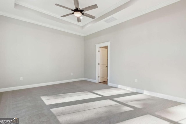 empty room with carpet, visible vents, a tray ceiling, and baseboards