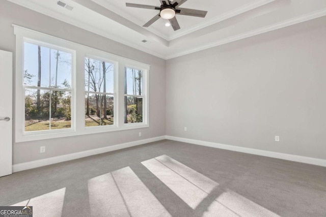 carpeted empty room featuring ornamental molding, a tray ceiling, visible vents, and baseboards